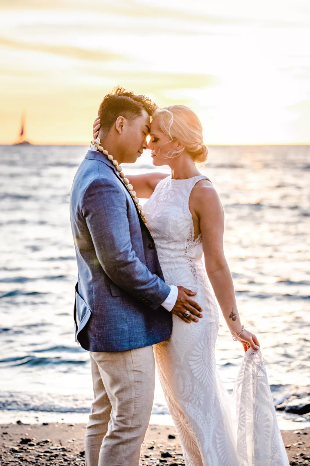 Sailboat behind bride and groom after Big Island wedding